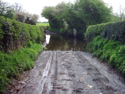 a muddy road leading to what looks like a very deep ford